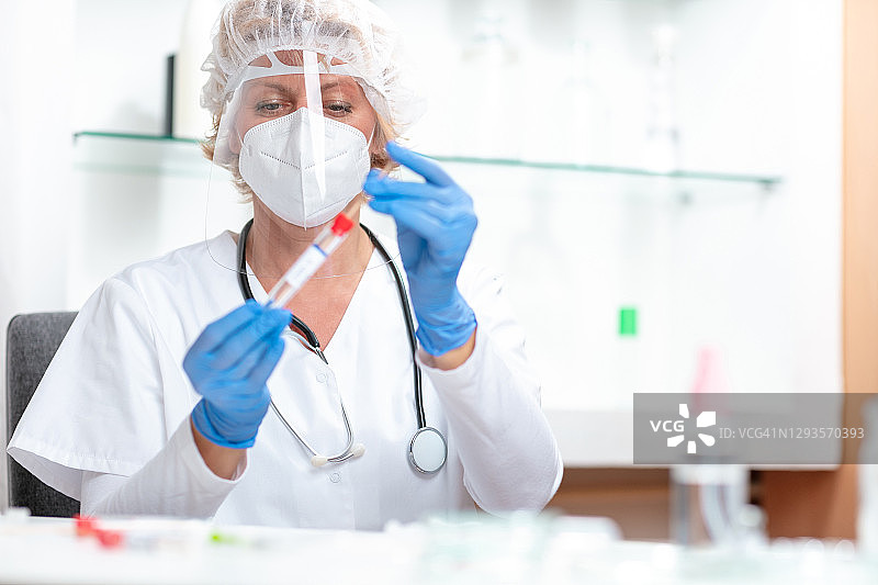 身穿防护服的女性医护人员手持COVID-19测试盒图片素材