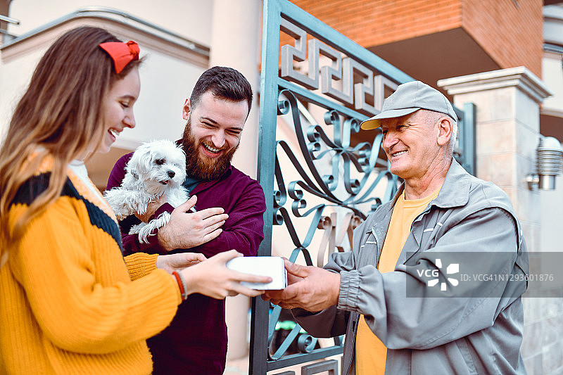 微笑的兄弟姐妹从邮递员那里取包裹图片素材
