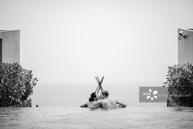 年轻情侣在无边泳池边亲吻图片素材