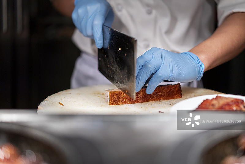 厨师在砧板上切割烤猪肉图片素材