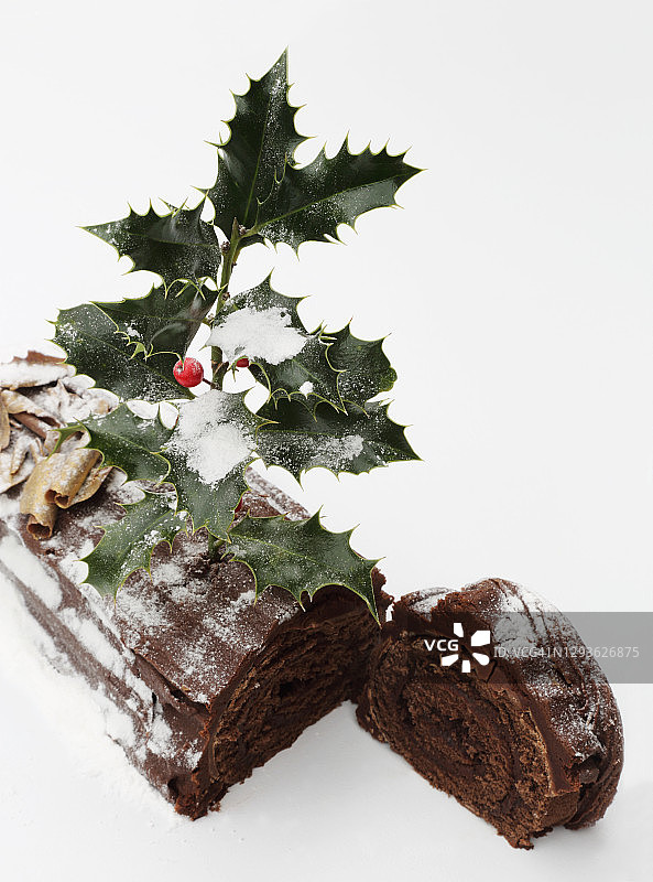 白色背景上装饰有冬青树的圣诞柴堆蛋糕切片图片素材
