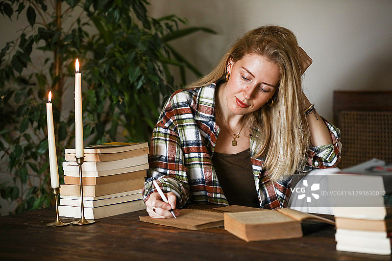 金发女人在烛光下阅读和写作图片素材