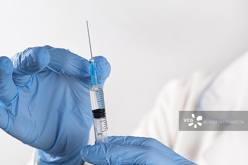 穿白大褂戴防护手套的医生拿着装有新冠疫苗的注射器图片素材