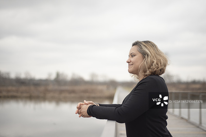 年轻女子 leaning 在小桥上图片素材