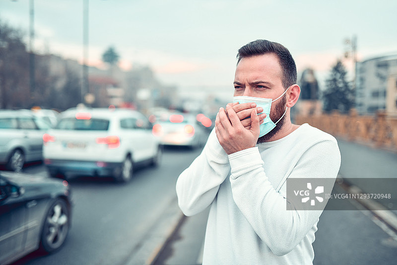 在市中心外戴着口罩咳嗽的男人图片素材