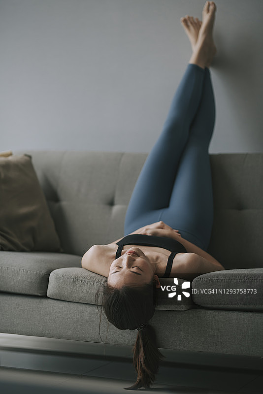 在客厅沙发上休息的亚洲年轻女子图片素材