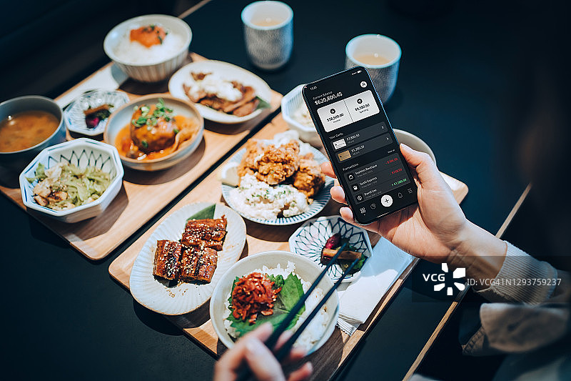 年轻亚洲女性在日式餐厅用手机银行管理账务图片素材