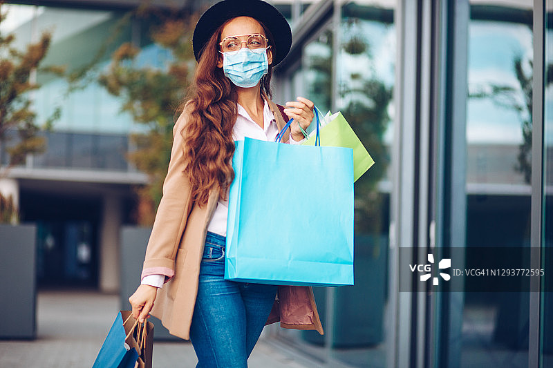 戴着防护口罩购物的漂亮女人图片素材
