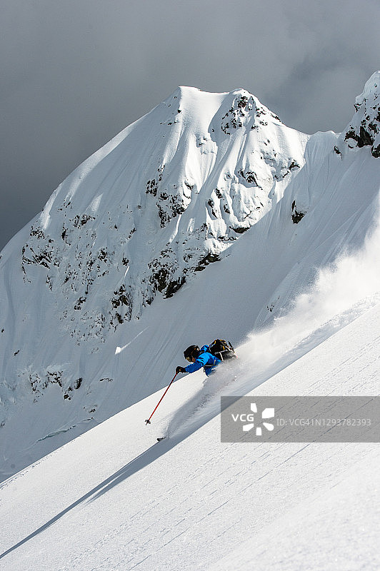 滑雪登山者在厚厚的粉雪中滑下陡坡图片素材