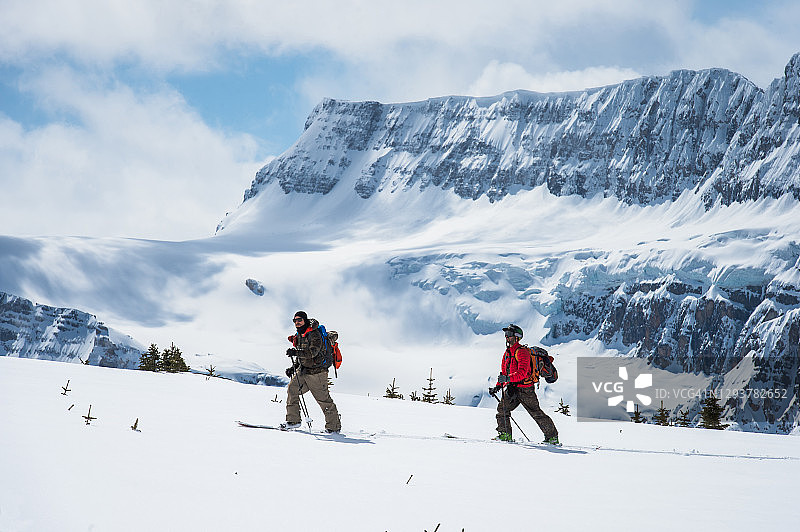 滑雪登山者登上森林山谷上方的斜坡图片素材
