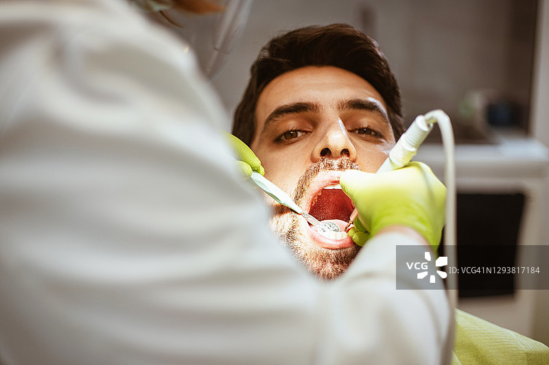 女牙医在牙科诊所检查一位年轻男子图片素材