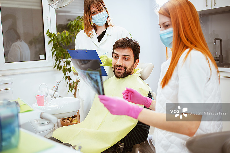 女牙医和一位助手正在观察X光片图片素材