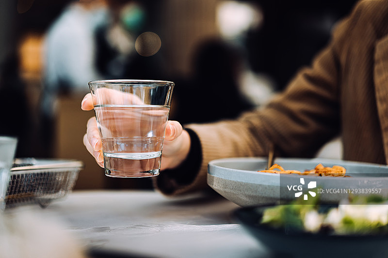 年轻亚洲女人在餐厅用餐时喝水特写图片素材