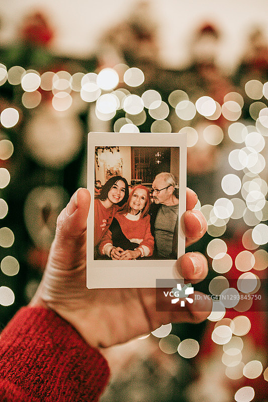 手持即时胶片照片：祖父母和孙女的家庭回忆图片素材