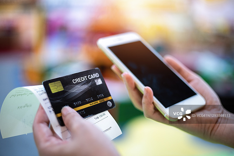 一位女士拿着手机和信用卡，信用卡概念图片素材