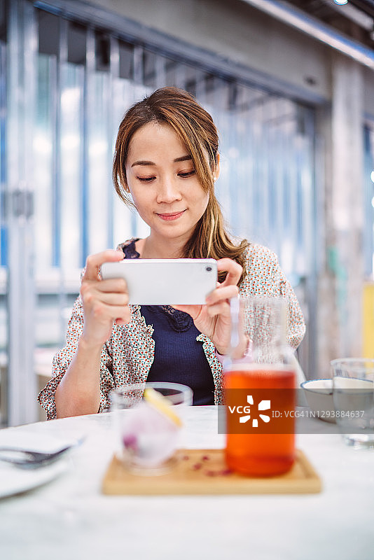 年轻的亚洲女性在餐厅拍摄她的餐点图片素材