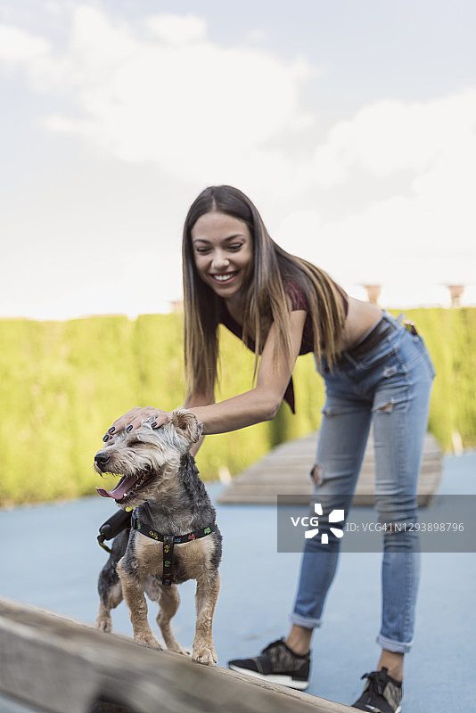 在公园景点训练她的狗的美丽年轻女子图片素材