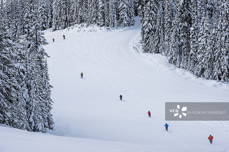山地自行车手在滑雪胜地的雪地里骑行图片素材