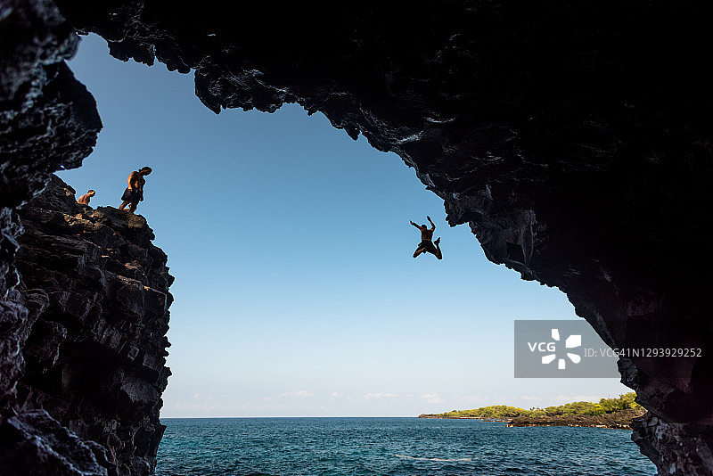 男人跳下悬崖，跃入大海图片素材