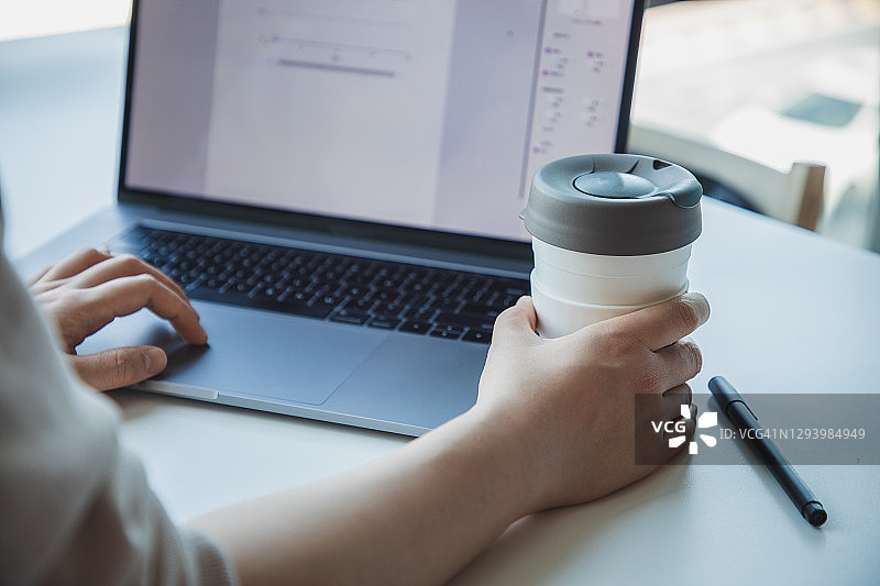 亚洲女人在办公室用笔记本电脑喝咖啡图片素材