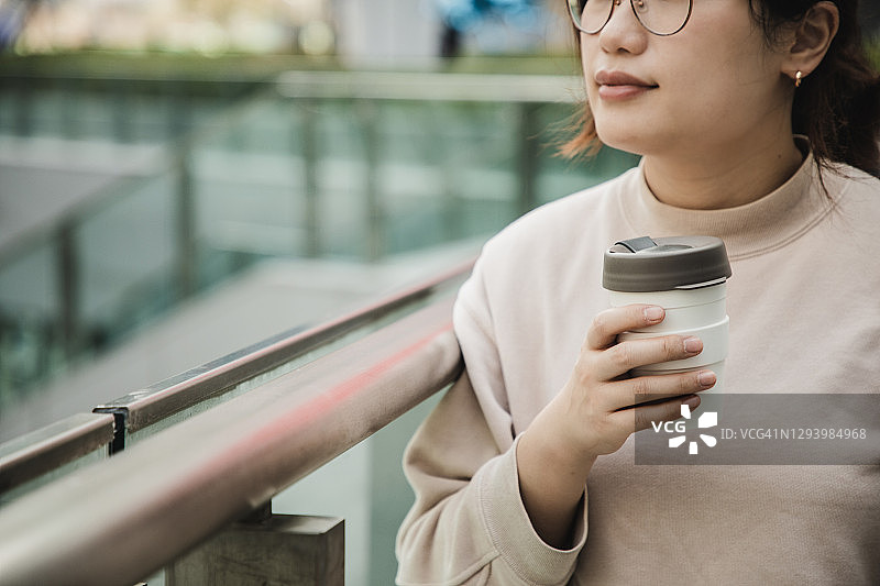 亚洲女人用可重复使用的杯子享受咖啡图片素材