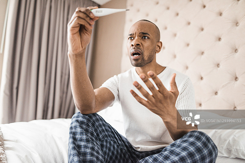 在家测量体温的焦虑男子图片素材