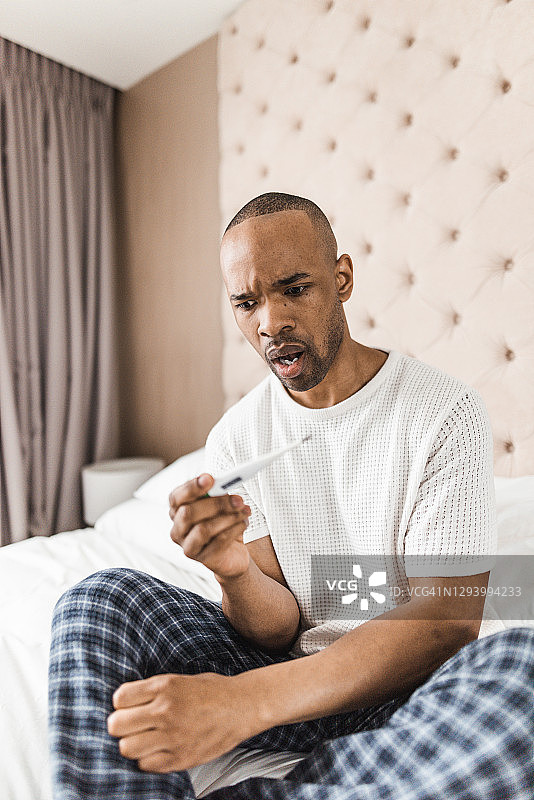 在家测量体温的焦虑男子图片素材