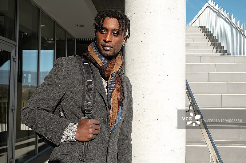 背着背包倚靠在街边柱子上的男商人肖像图片素材