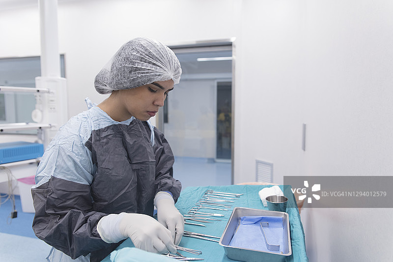 在手术室整理医疗器械的拉丁裔年轻女外科技术员图片素材