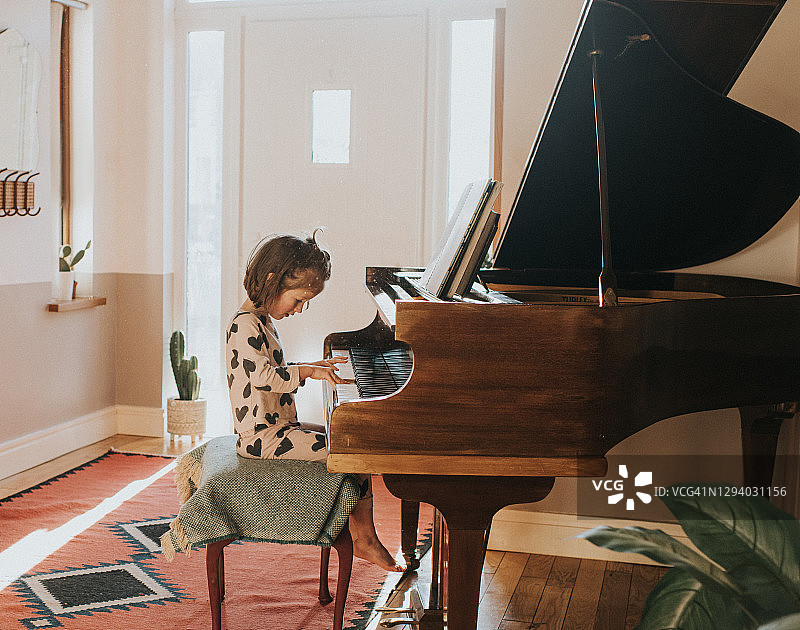 小女孩在家庭环境中弹奏大钢琴图片素材