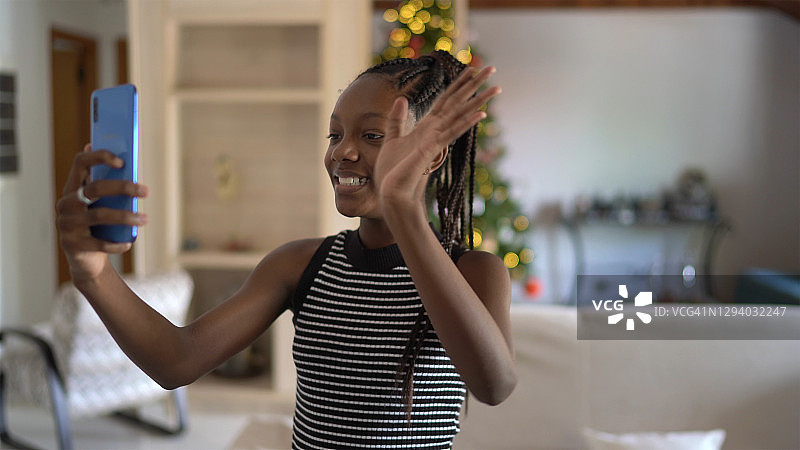 少女在家中对着智能手机挥手进行视频通话图片素材
