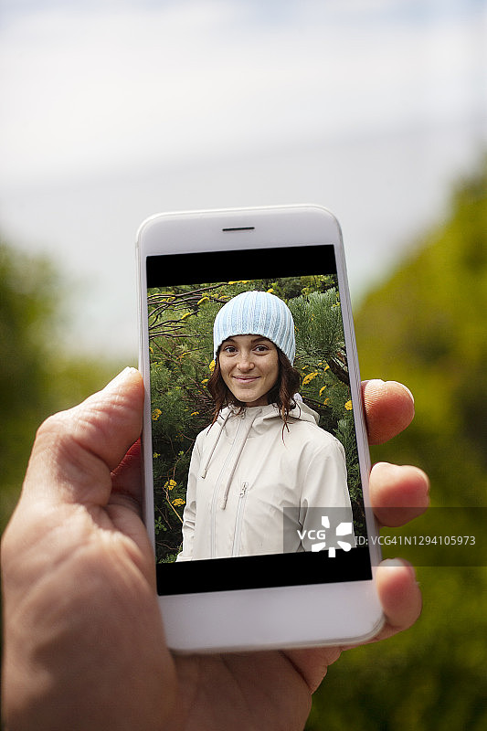 手持年轻女子在自然中欣赏鲜花照片图片素材