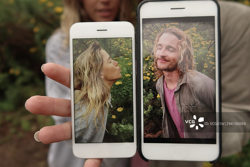 一对情侣并排展示手机上的浪漫照片图片素材