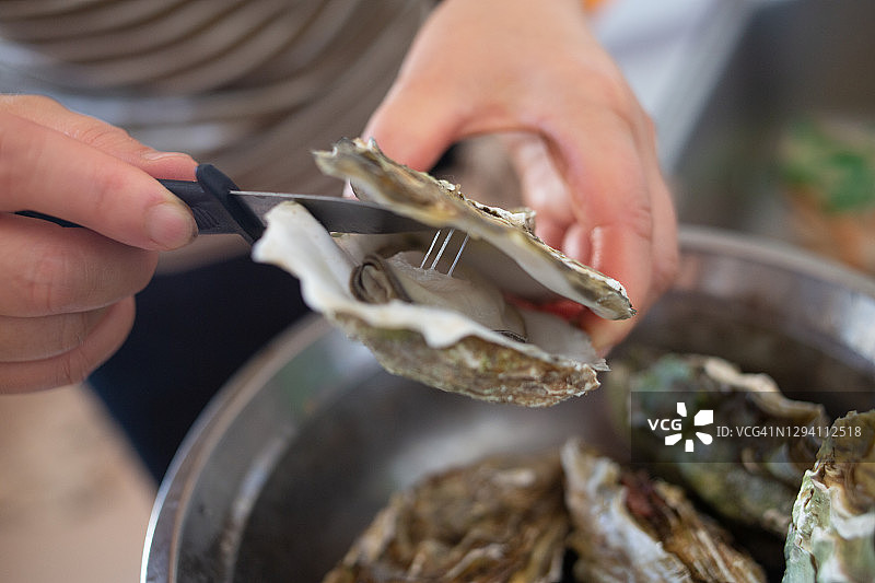 女人用刀打开牡蛎壳特写图片素材