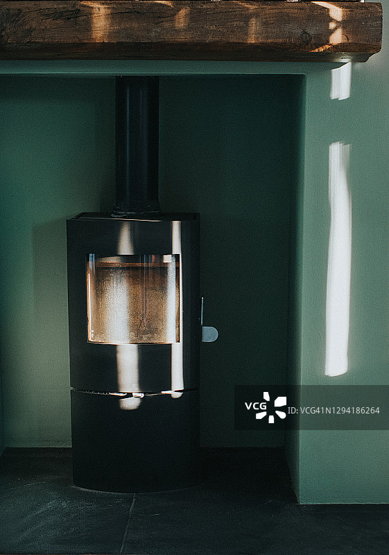 绿色墙壁旁的现代燃木火炉图片素材