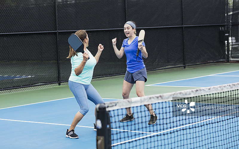 西班牙裔妇女和成年女儿打匹克球图片素材