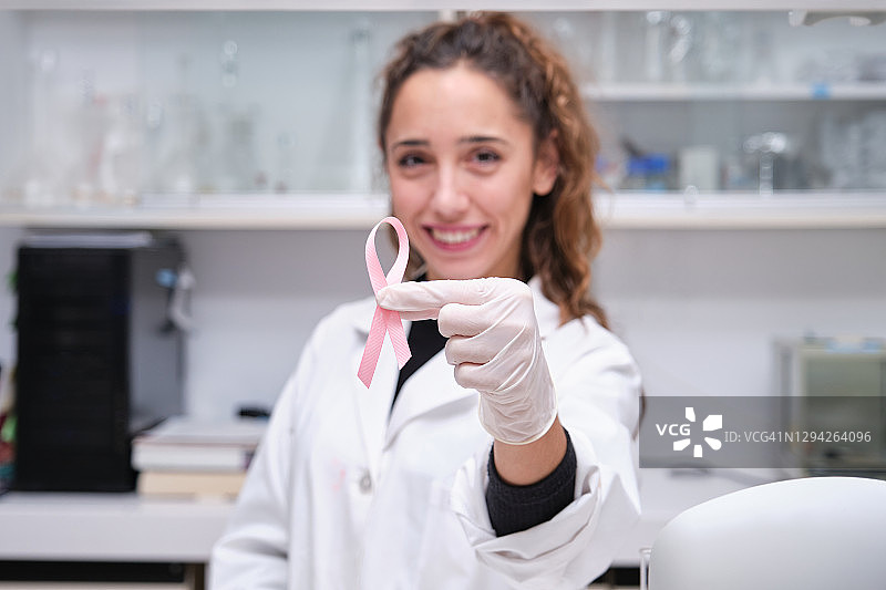 年轻女科学家手持粉红丝带，关注乳腺癌图片素材