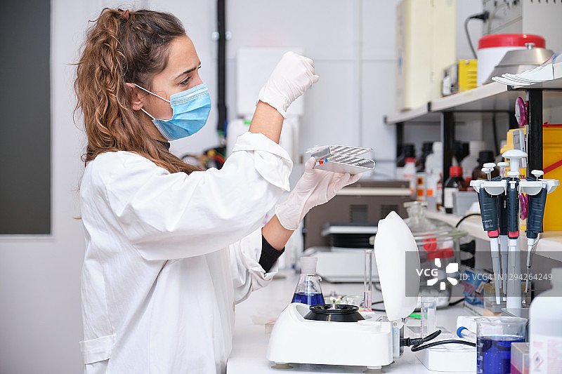 年轻女科学家在实验室用离心机对试管中的DNA进行采样研究图片素材