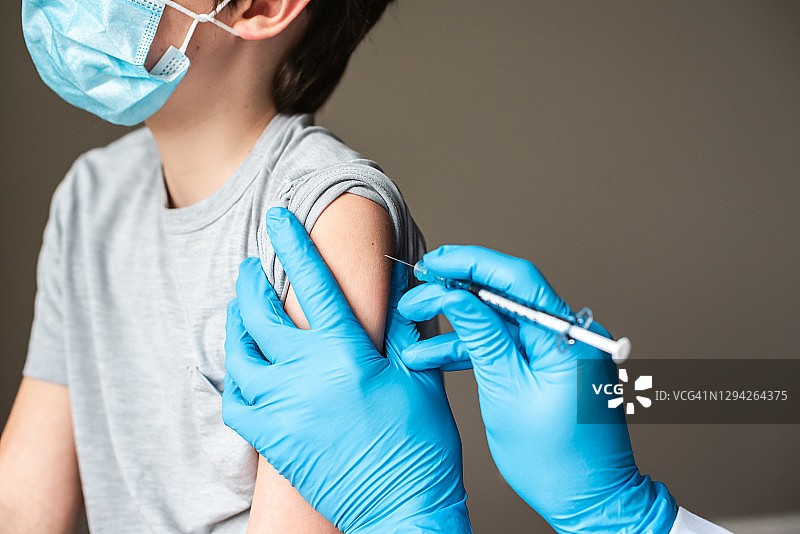 儿童戴着口罩接受医生注射疫苗图片素材