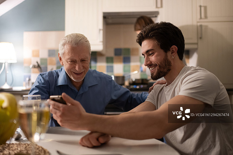 年长的父亲支持儿子一起看照片图片素材