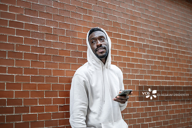 非洲男子在城市中使用智能手机，面带微笑图片素材