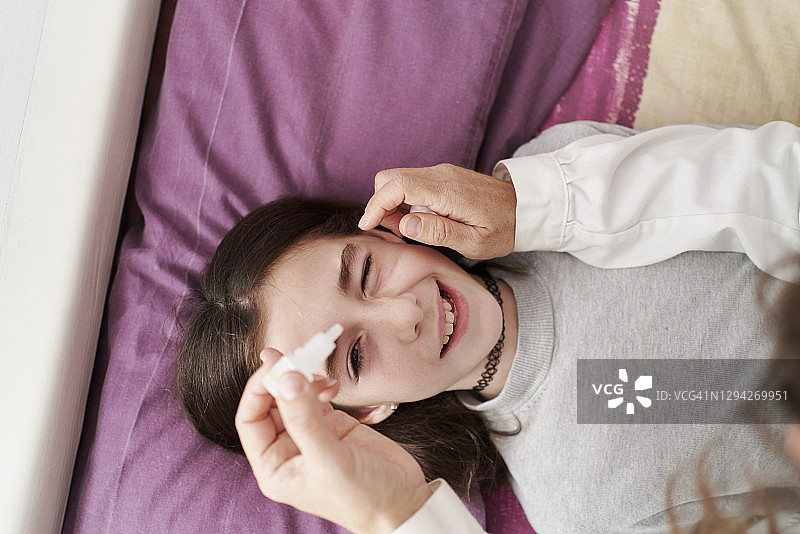 俯视：女医生微笑地给床上小女孩滴眼药水图片素材