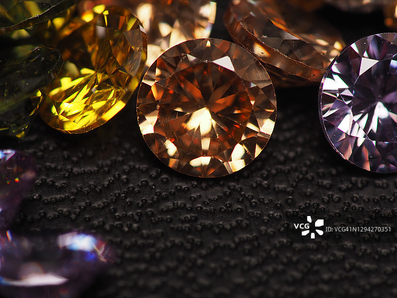 美丽、闪亮、多色钻石水晶宝石的特写镜头，在黑色皮革上拍摄图片素材