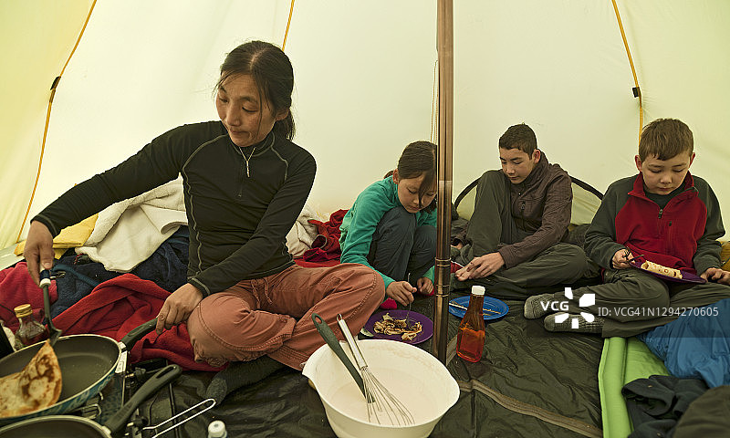 母亲在帐篷里为孩子们做薄饼图片素材