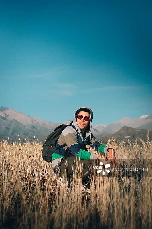 戴着太阳镜在山附近田野里微笑的男人图片素材