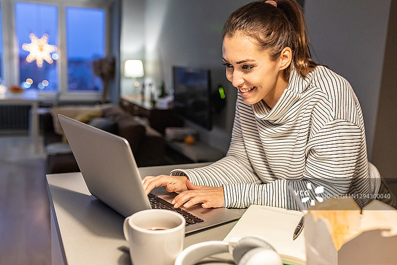 年轻女人在家中深夜使用笔记本电脑工作图片素材