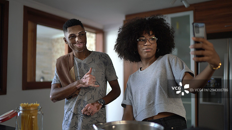在家烹饪时进行视频通话的年轻情侣或兄妹图片素材