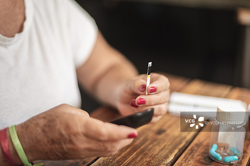 老年妇女在家用血糖仪检测血糖特写图片素材