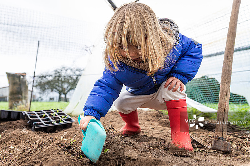 可爱的小女孩在温室里玩玩具铲子图片素材