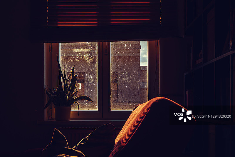 阳光明媚的午后，客厅里有一个红色沙发和脏窗户图片素材